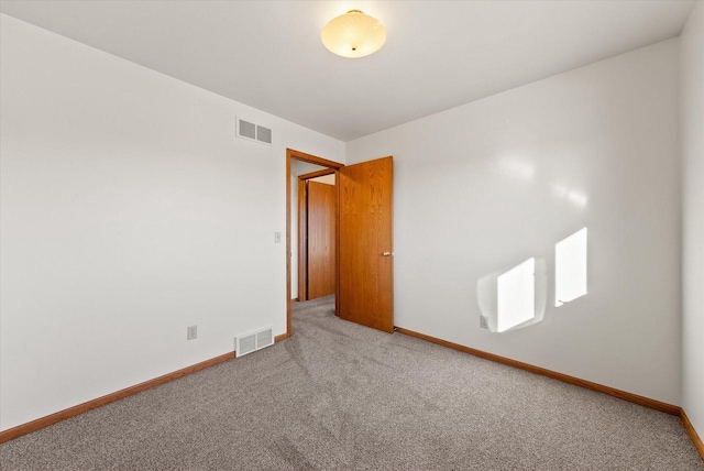 carpeted spare room featuring visible vents and baseboards