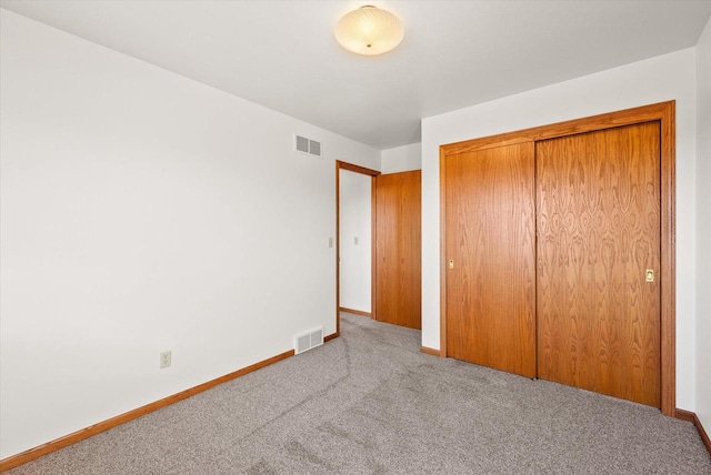 unfurnished bedroom featuring carpet, a closet, visible vents, and baseboards