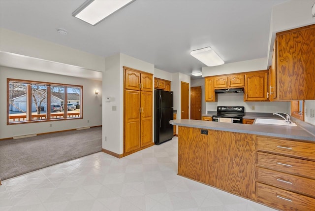 kitchen featuring electric stove, freestanding refrigerator, a peninsula, under cabinet range hood, and a sink