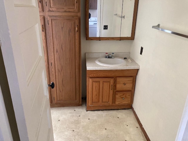 bathroom with washer / dryer, vanity, baseboards, and tile patterned floors