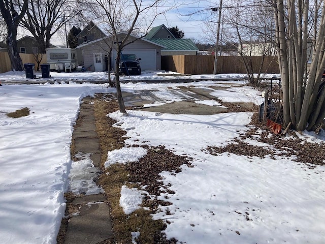 yard layered in snow with a garage and fence