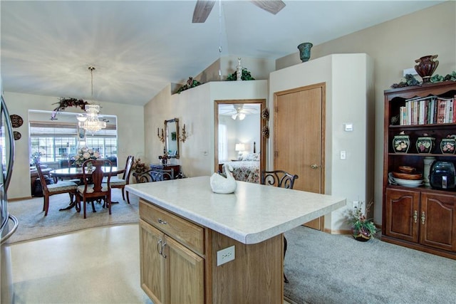 kitchen featuring lofted ceiling, a kitchen island, light countertops, and ceiling fan with notable chandelier