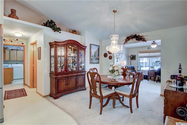 dining area featuring ceiling fan with notable chandelier, separate washer and dryer, baseboards, and light colored carpet