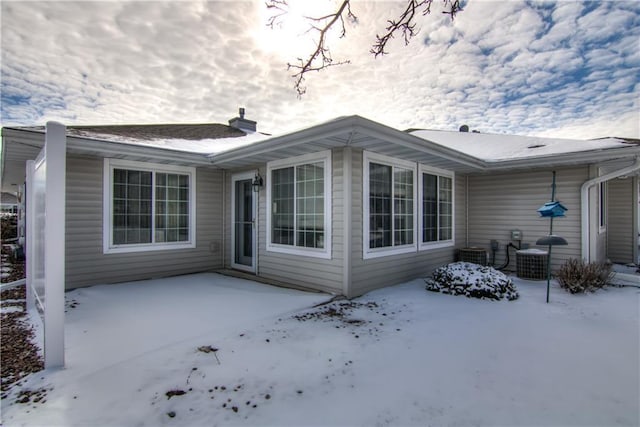 snow covered back of property with a patio area