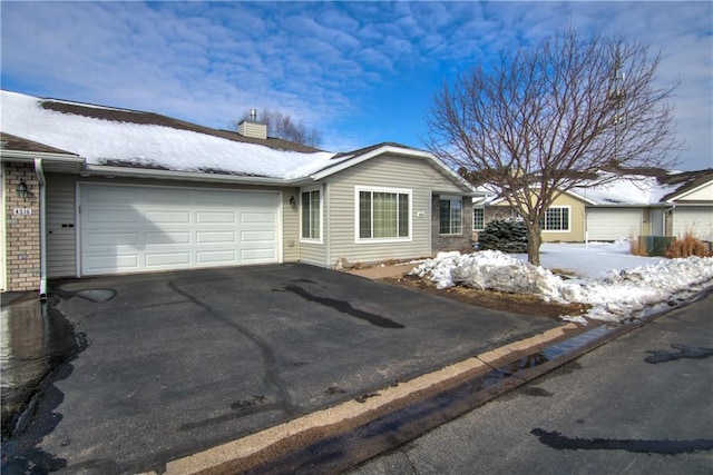 view of front of home featuring aphalt driveway, a chimney, and an attached garage