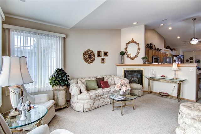 living area with a ceiling fan, a glass covered fireplace, carpet, vaulted ceiling, and recessed lighting