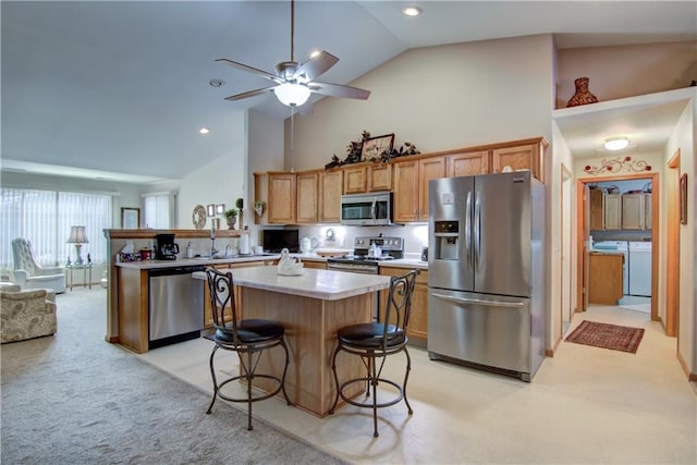 kitchen featuring stainless steel appliances, light countertops, light colored carpet, independent washer and dryer, and a peninsula