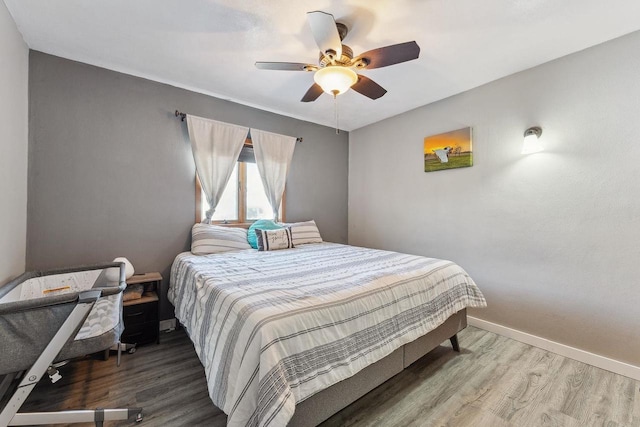 bedroom featuring a ceiling fan, baseboards, and wood finished floors