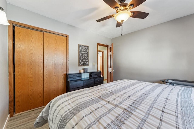 bedroom with a closet, wood finished floors, a ceiling fan, and baseboards