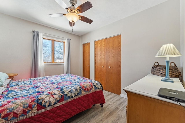 bedroom with light wood finished floors, a ceiling fan, and multiple closets