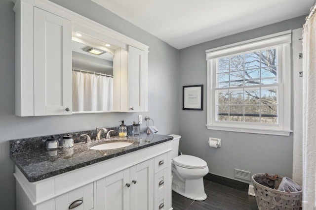 bathroom featuring toilet, baseboards, visible vents, and vanity