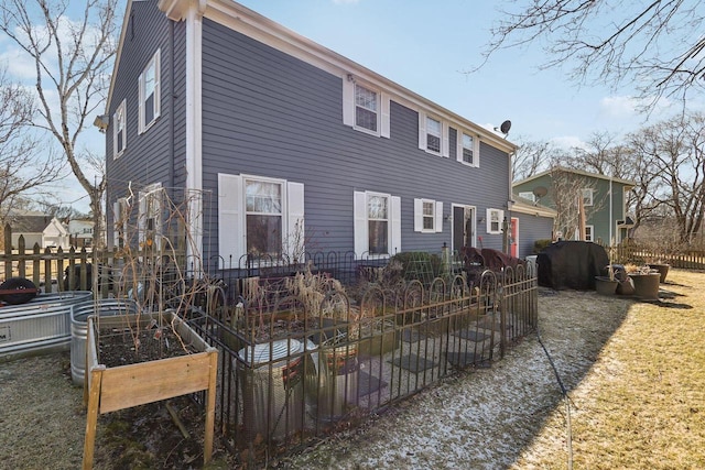 back of property featuring a garden and fence