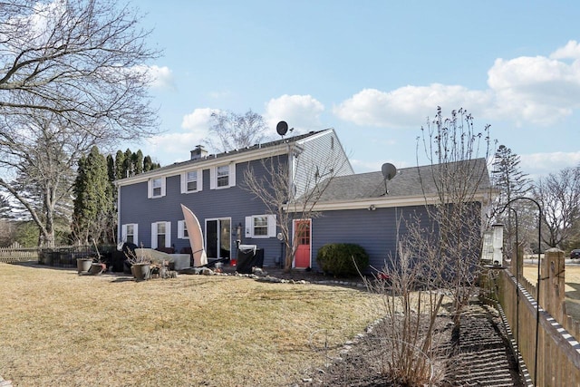 back of property featuring a yard, a chimney, an attached garage, and fence