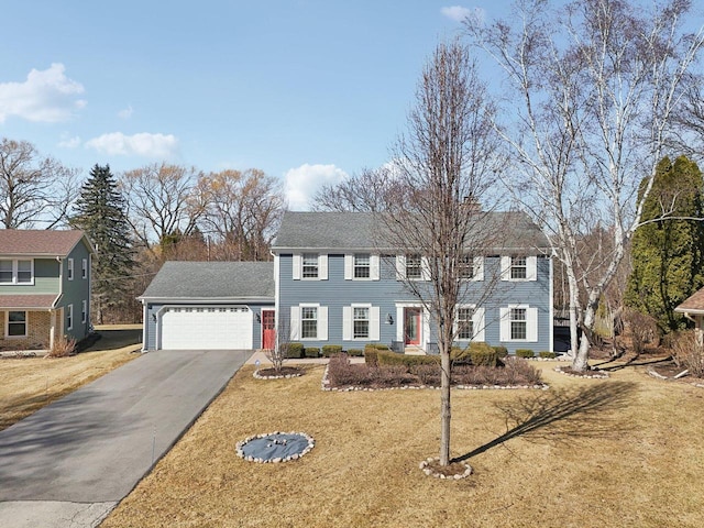 colonial home featuring a garage, aphalt driveway, and a front yard