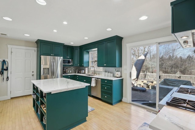 kitchen featuring a healthy amount of sunlight, appliances with stainless steel finishes, green cabinets, and a sink