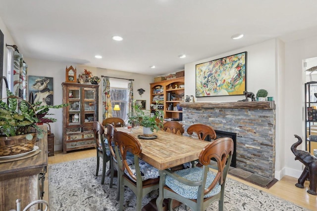 dining area with light wood-type flooring, a fireplace, and recessed lighting