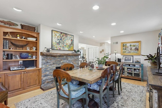 dining area featuring light wood-type flooring, a fireplace, visible vents, and recessed lighting