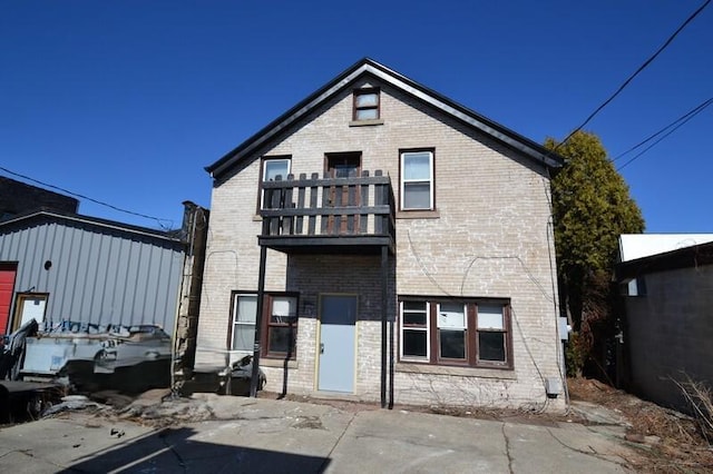 rear view of property with a balcony and brick siding