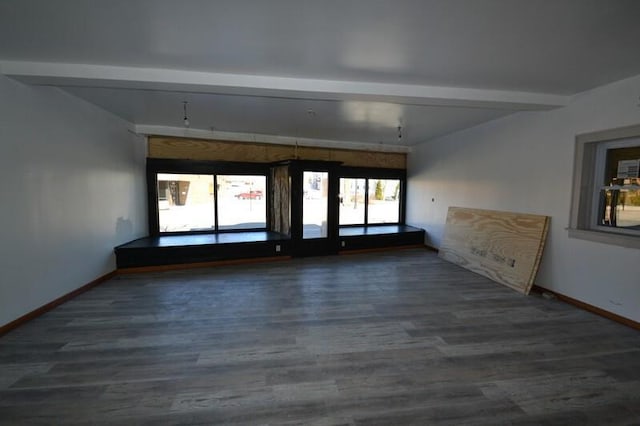 unfurnished room featuring beamed ceiling, baseboards, and wood finished floors