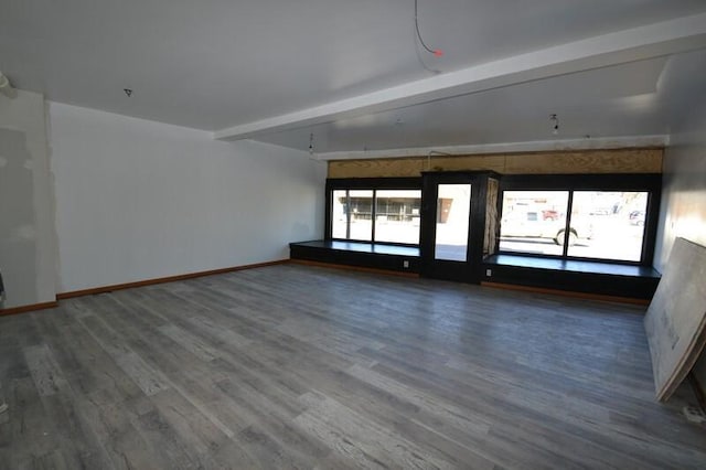 unfurnished room with beamed ceiling, wood finished floors, and baseboards