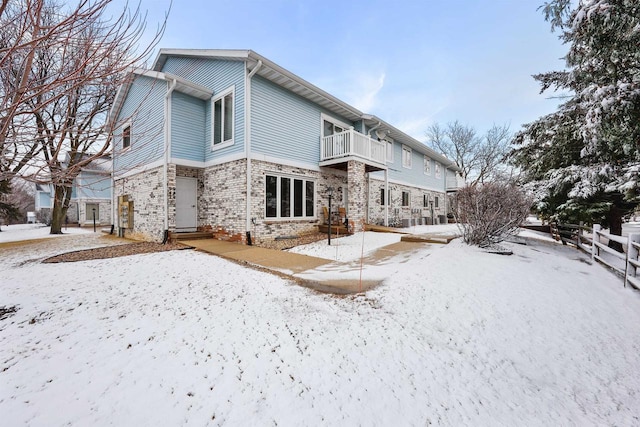 snow covered property with a balcony and fence