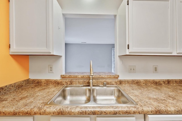 kitchen featuring white cabinets, light countertops, and a sink