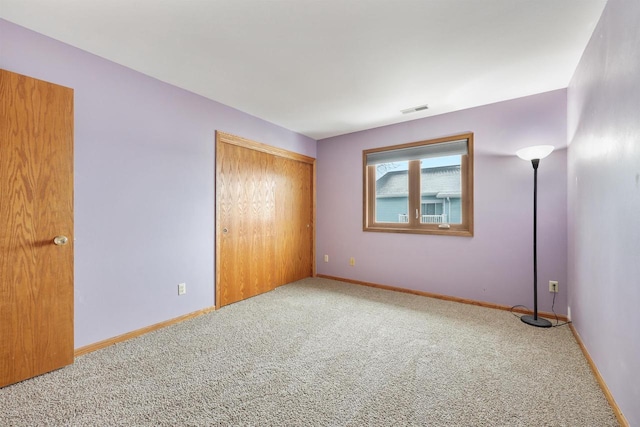 unfurnished bedroom with a closet, carpet flooring, visible vents, and baseboards