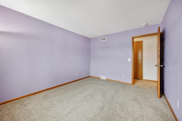 carpeted spare room featuring visible vents and baseboards