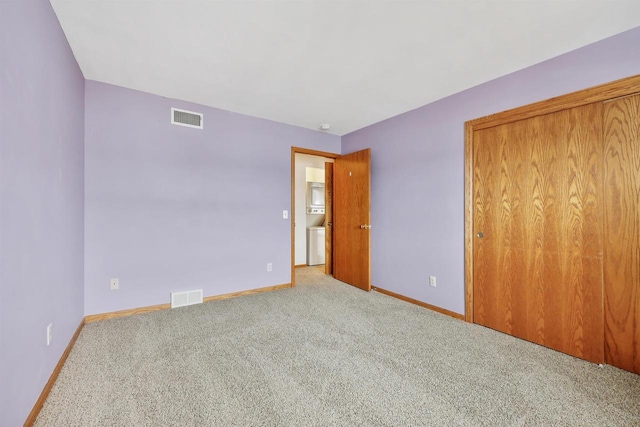 unfurnished bedroom with a closet, carpet, visible vents, and baseboards