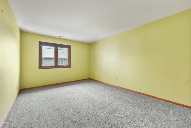 empty room with carpet flooring, visible vents, and baseboards