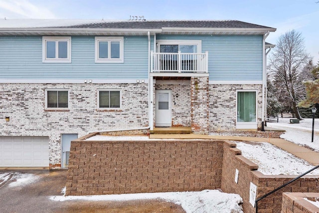 townhome / multi-family property featuring a garage, brick siding, and a balcony