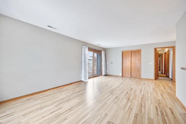 spare room with visible vents, light wood-style flooring, and baseboards