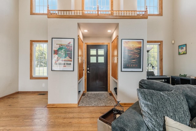 foyer entrance with recessed lighting, baseboards, a high ceiling, and wood finished floors