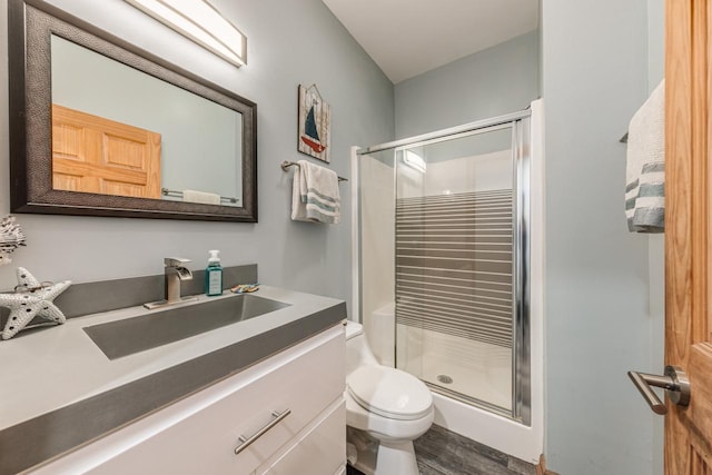 full bathroom with a stall shower, vanity, toilet, and wood finished floors