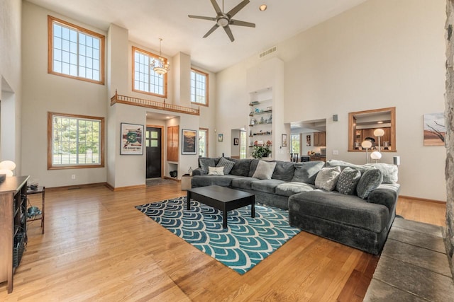 living room with ceiling fan with notable chandelier, visible vents, baseboards, and wood finished floors