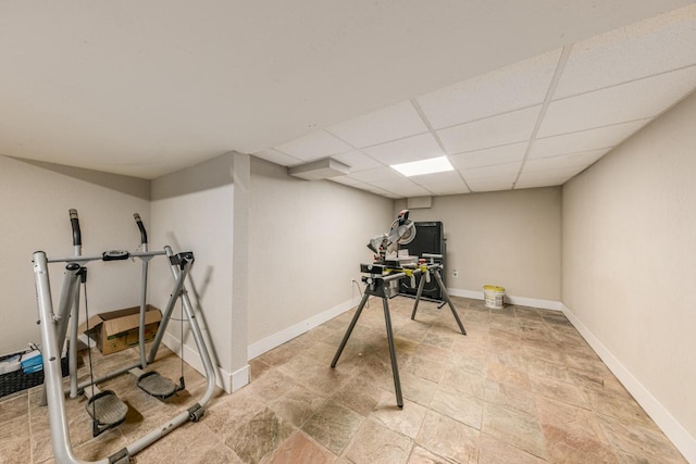 exercise room with a paneled ceiling and baseboards