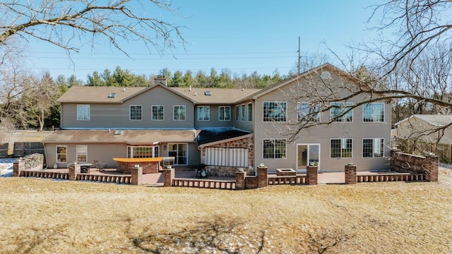 back of house featuring a chimney, a patio area, a wooden deck, and a jacuzzi