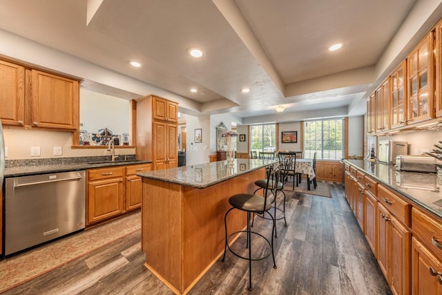 kitchen featuring dark wood-type flooring, a tray ceiling, dishwasher, and a kitchen breakfast bar