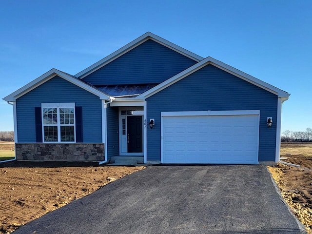 single story home with a garage, stone siding, and aphalt driveway