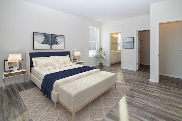 bedroom with connected bathroom, baseboards, and wood finished floors