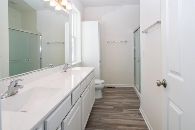 bathroom featuring toilet, a stall shower, a sink, and wood finished floors