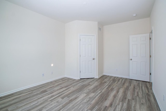 empty room with baseboards, visible vents, and light wood finished floors