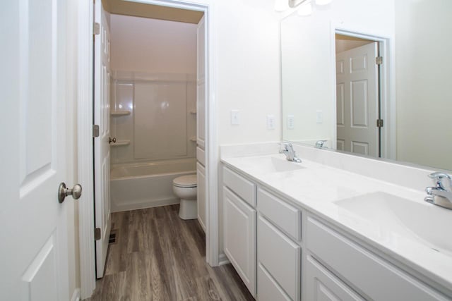 full bathroom with double vanity, toilet, a sink, and wood finished floors