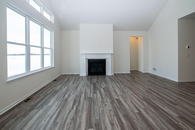 unfurnished living room with lofted ceiling, a fireplace, dark wood finished floors, and a healthy amount of sunlight