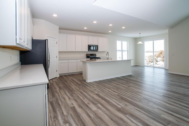 kitchen featuring recessed lighting, stainless steel appliances, wood finished floors, a sink, and white cabinets