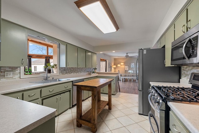 kitchen with green cabinets, light tile patterned flooring, appliances with stainless steel finishes, and a sink