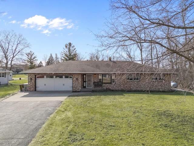 ranch-style home with brick siding, an attached garage, a shingled roof, a front lawn, and driveway