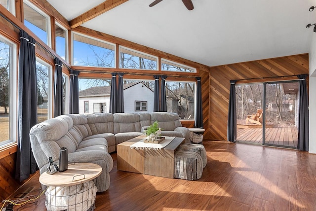 living area with wood finished floors, a healthy amount of sunlight, wood walls, and vaulted ceiling with beams