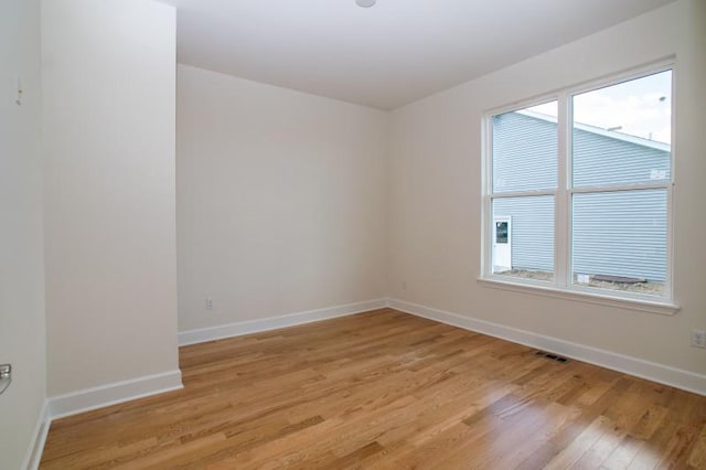 empty room with light wood-type flooring, baseboards, visible vents, and a wealth of natural light