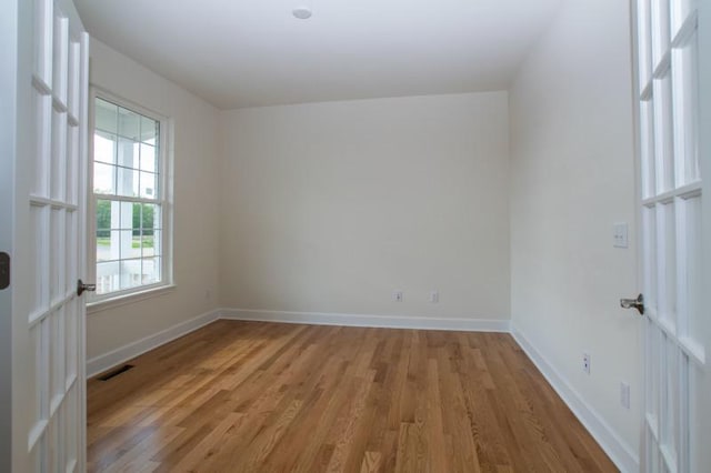 spare room featuring light wood-style flooring, visible vents, and baseboards